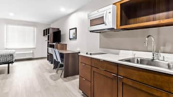 A modern kitchen with a built-in microwave, stainless steel sink, and wooden cabinets.
