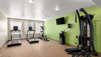 Une salle de sport équipée de tapis de course, d’un appareil elliptique et d’une machine de musculation.