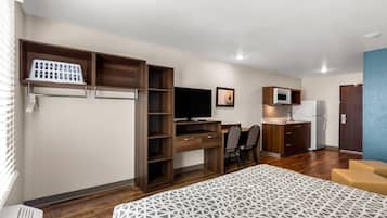 Habitació d'hotel senzilla amb llit, escriptori amb ordinador, televisió, petita cuina i zona de seients.