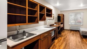 Una cocina moderna con armarios de madera, un lavamanos de acero inoxidable y un microondas integrado.
