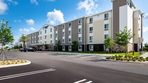 A multi-story hotel with a modern design, featuring a prominent entrance and a parking area in front.