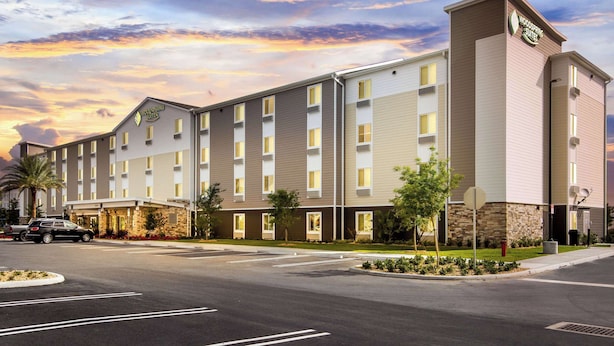Un hotel moderno con techo plano, múltiples ventanas y un letrero que indica que es un Woodspring Suites.