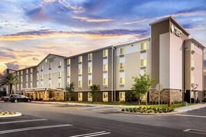 Un hotel moderno con techo plano, múltiples ventanas y un letrero que indica que es un Woodspring Suites.