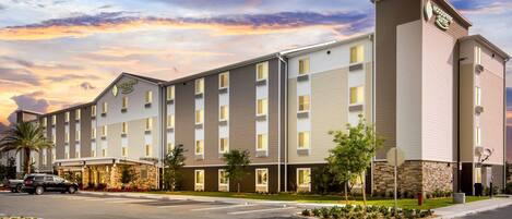 A multi-story hotel with a flat roof, large windows, and a stone facade.