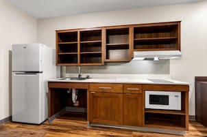 Una cocina compacta con armarios de madera, un refrigerador blanco, un microondas y un lavamanos.