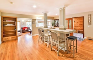 A spacious living area with a wooden dining table, chairs, and a built-in bookshelf.