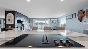 Una cocina moderna con encimera de mármol blanco y negro, horno empotrado y una isla grande con placa de inducción negra.