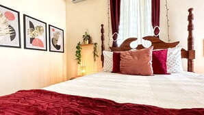 A bed with a wooden headboard, a red blanket, and multiple pillows. - Boho chic 2 bedroom in Miramar  1B (San Juan)