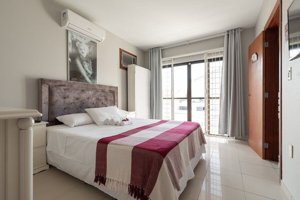 Une chambre à coucher avec un lit, une table de chevet, une fenêtre avec des rideaux et une porte.