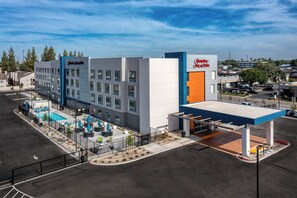 A hotel with a swimming pool, outdoor seating, and a gas station. - Hampton Inn & Suites Bakersfield Central (Bakersfield)