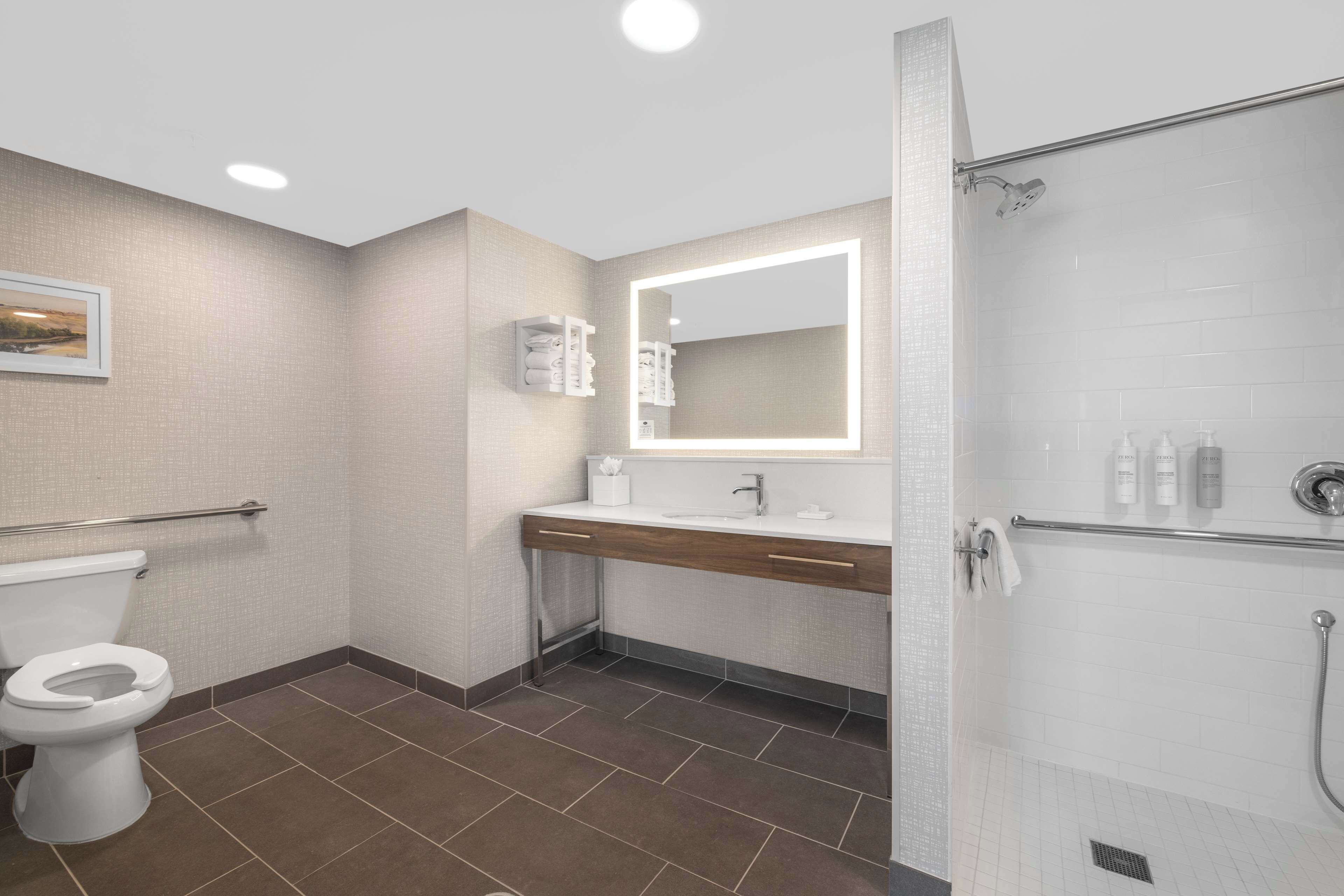 Une salle de bain moderne équipée de toilettes, d’un lavabo, d’un miroir et d’une douche.