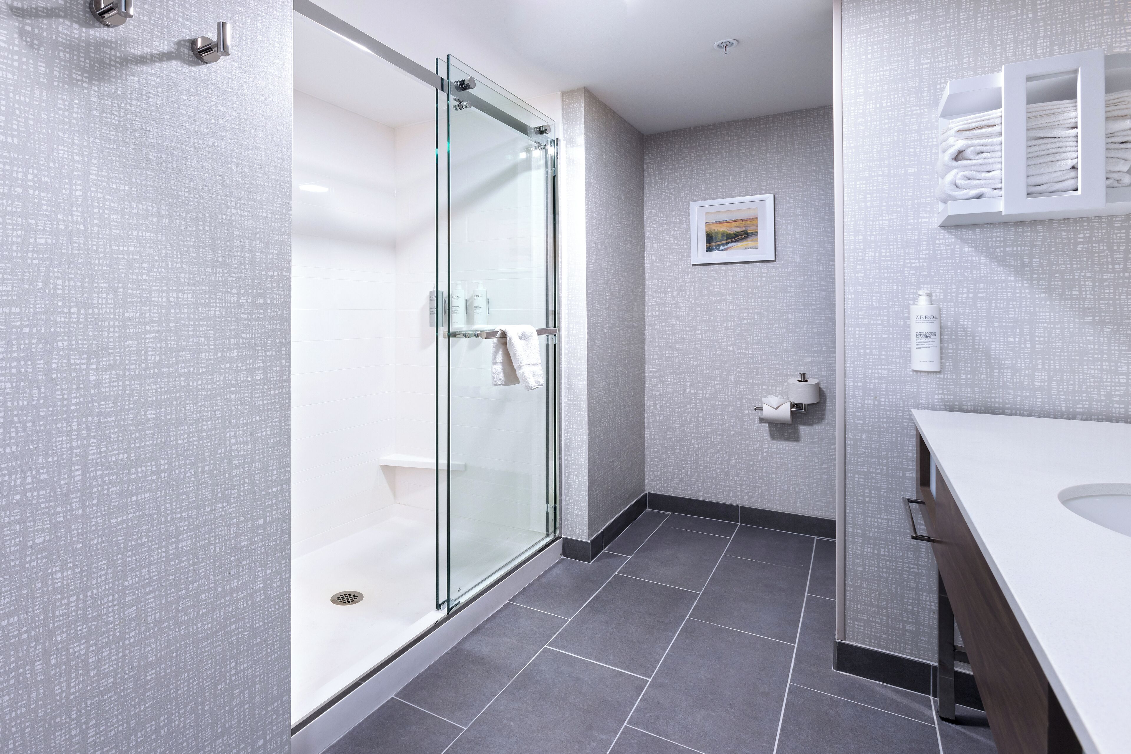 Une salle de bain moderne avec une douche à parois de verre, un lavabo blanc et un porte-serviettes.