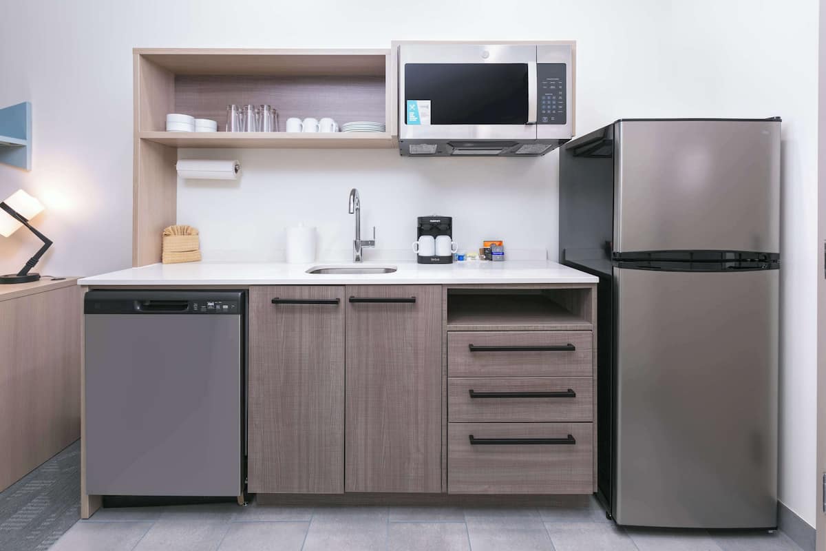 A compact kitchen with a dishwasher, a microwave, a refrigerator, and a sink.