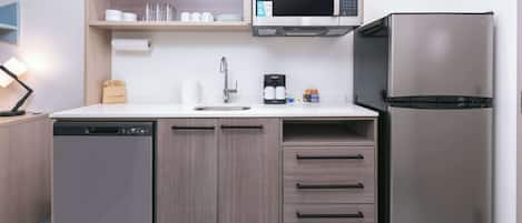 Una cocina compacta equipada con lavavajillas, microondas, refrigerador y pileta.
