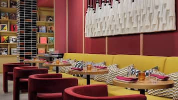 Un interior moderno con un sofá amarillo, sillas rojas y una estantería con discos de vinilo.