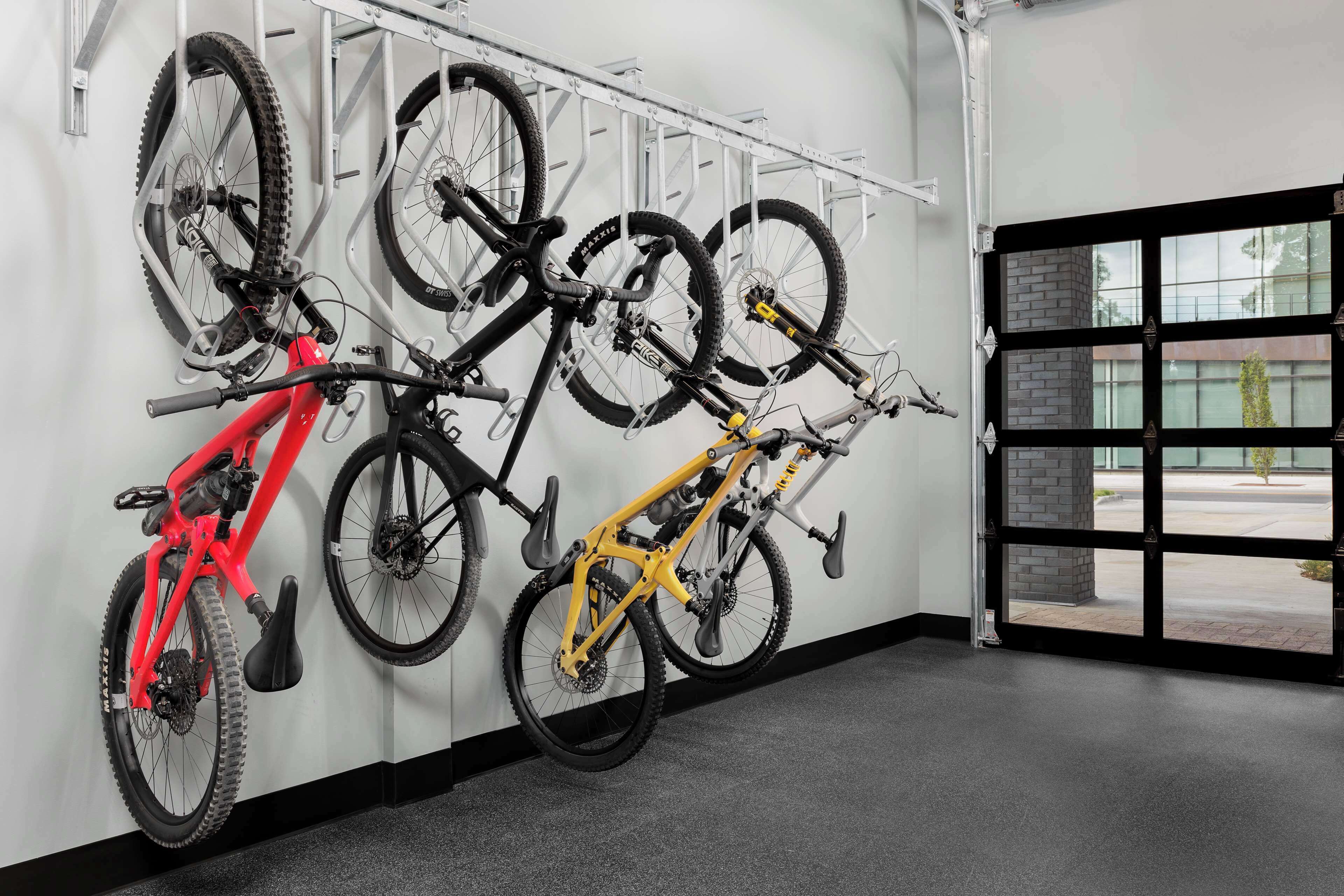 A bike rack with multiple bicycles, a red and a yellow bike, and a door leading outside.