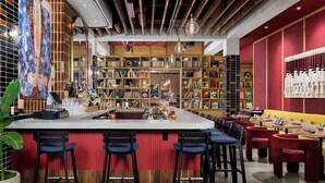 A modern bar area with a central island, bar stools, and a variety of bookshelves in the background.