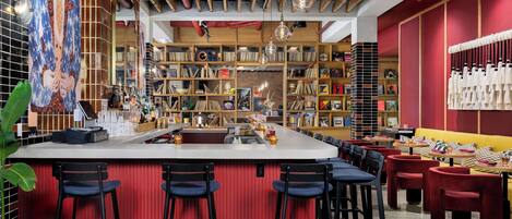 A modern bar area with a central island, bar stools, and a variety of bookshelves in the background.