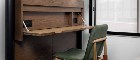 A modern room with a wooden desk, a green chair, and a lamp.