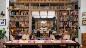 A dining area with a long table set for four, surrounded by bookshelves filled with books and decorative items.