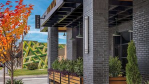 A modern building with a prominent 'JUNTO' sign, brick walls, and a green patterned facade.