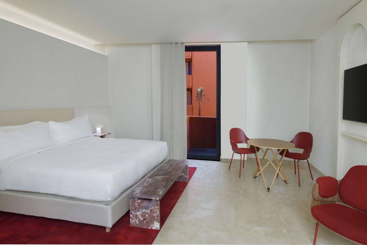 Une chambre d’hôtel avec un grand lit, une petite table avec des chaises et un téléviseur fixé au mur.