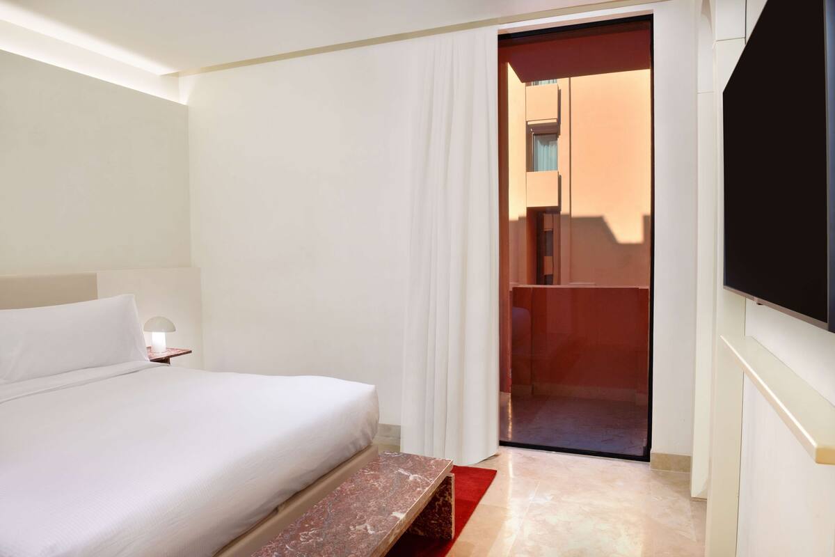 Une chambre d’hôtel équipée d’un lit, d’une table de chevet et d’un téléviseur fixé au mur.