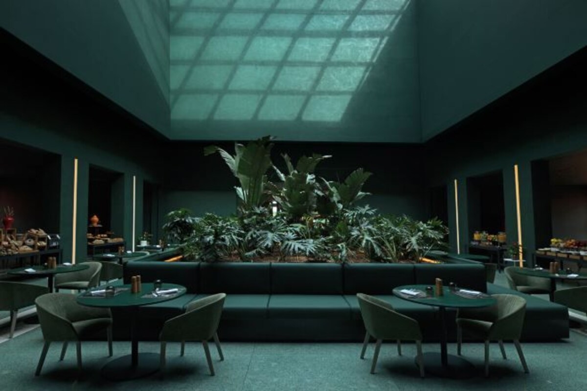 Een modern interieur met een centraal zitelement, groene wanden en een dakraam.