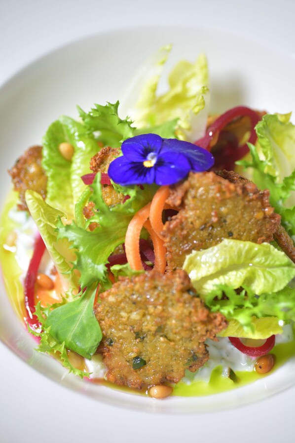 A dish with various vegetables and a blue flower.