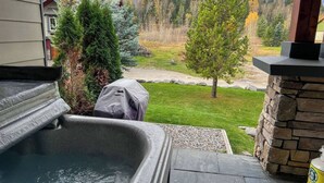 Un jacuzzi con revestimiento de piedra, una parrilla techada y una pared de piedra.