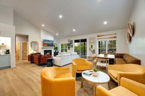 A spacious living area with a fireplace, a dining table, and yellow armchairs.