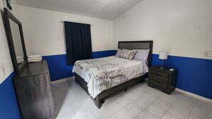 A bedroom with a bed, a nightstand, a dresser, a window with curtains, and a mirror. - Duplex Back Apartment (Vero Beach)