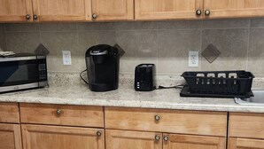 A kitchen with wooden cabinets, a microwave, a coffee maker, and a toaster on the countertop. - Duplex Back Apartment (Vero Beach)