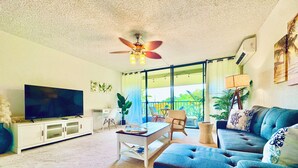 A living room with a television, sofa, coffee table, and a ceiling fan. - Peaceful Retreat • 5 min Walk to Town, Pier & Beach • Free Parking (Kailua-Kona)