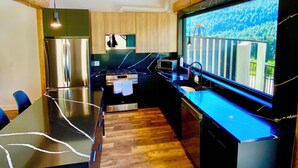 A modern kitchen with a large island, stainless steel appliances, and a view of a balcony. - Timberwolf A Cabin at Sasquatch Mountain  *HOT TUB* GAMES ROOM* (Agassiz)