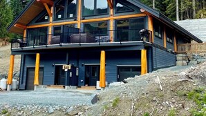 A modern two-story cabin with large windows, a balcony, and a stone foundation. - Timberwolf A Cabin at Sasquatch Mountain  *HOT TUB* GAMES ROOM* (Agassiz)