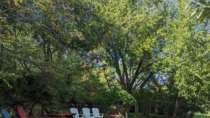 Une piscine rectangulaire avec un escalier en métal, entourée d’une terrasse en briques. On y trouve plusieurs chaises Adirondack blanches et rouges, ainsi que quelques chaises bleues.