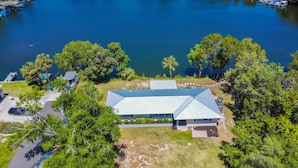 An aerial view of a house with a metal roof, surrounded by lush greenery and a body of water. - Welcome to the scallop shack! Newly renovated and on the water in Crystal River! (Crystal River)