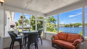 A covered patio with wicker furniture, a round table, and a sofa with a patterned cushion. - Welcome to the scallop shack! Newly renovated and on the water in Crystal River! (Crystal River)