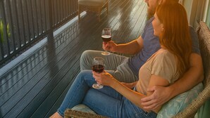 A couple sitting on a wooden deck with a view of a sunset.