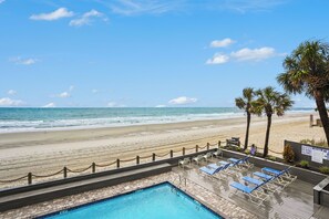 A pool area with a view of the beach and ocean.