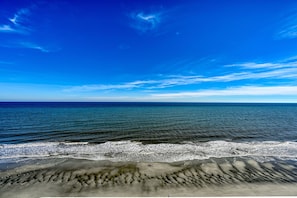 Une plage avec des vagues, un ciel dégagé et un horizon lointain.