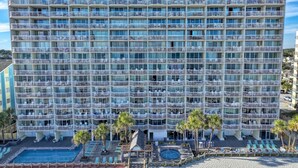A multi-story hotel with balconies, a pool, and a beach area. - Oceanfront 2bed/2bath-Water's Edge Resort-711 Indoor/Outdoor Pool & Hot Tub (Garden City Beach)