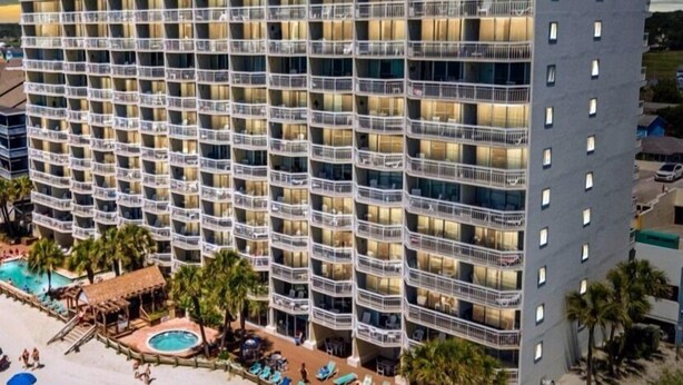 A multi-story hotel with balconies, a pool area with sun loungers, and a beachside location. - Oceanfront 2bed/2bath-Water's Edge Resort-711 Indoor/Outdoor Pool & Hot Tub (Garden City Beach)