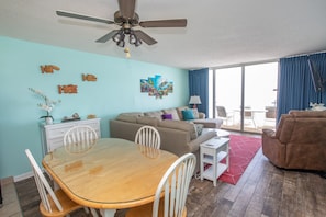 A living room with a dining table, chairs, a sofa, and a ceiling fan.