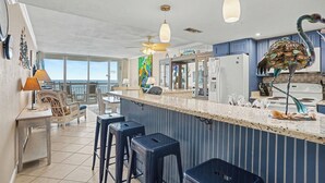 Een moderne keuken met een bar, grote ramen en een plafondventilator.