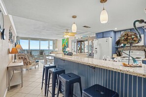 Une cuisine moderne dotée d’un coin bar, de grandes fenêtres et d’un ventilateur de plafond.
