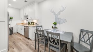 Una cucina moderna con mobili bianchi, un tavolo da pranzo con sedie e un adesivo murale raffigurante una testa di cervo.