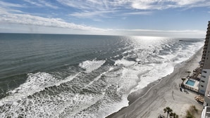 A beachfront hotel with a pool, ocean view, and a pier in the distance. - Oceanfront 1bed/2bath-Water's Edge Resort-1206 Indoor/Outdoor Pool & Hot Tub (Garden City Beach)