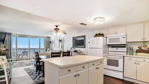 A kitchen with a central island, white cabinets, a microwave, and a refrigerator. - Oceanfront 2bed/2bath-Water's Edge Resort-602 Indoor/Outdoor Pool & Hot Tub (Garden City Beach)